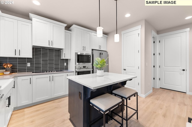 kitchen featuring backsplash, light wood-type flooring, appliances with stainless steel finishes, decorative light fixtures, and white cabinetry