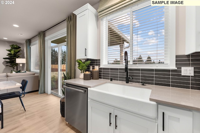 kitchen with tasteful backsplash, white cabinetry, dishwasher, and light wood-type flooring