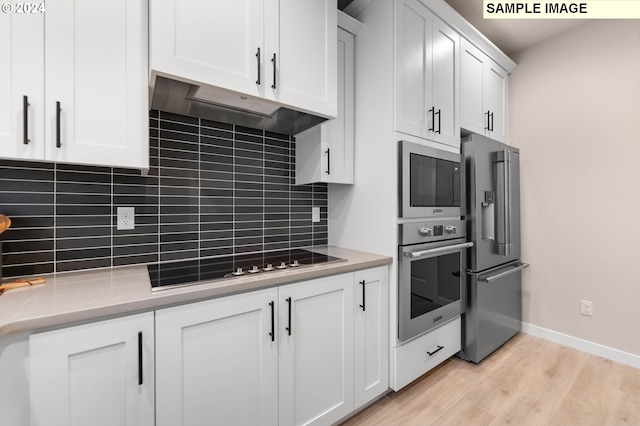 kitchen with white cabinets, light hardwood / wood-style floors, backsplash, and appliances with stainless steel finishes