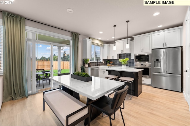 kitchen featuring a center island, white cabinets, hanging light fixtures, appliances with stainless steel finishes, and tasteful backsplash