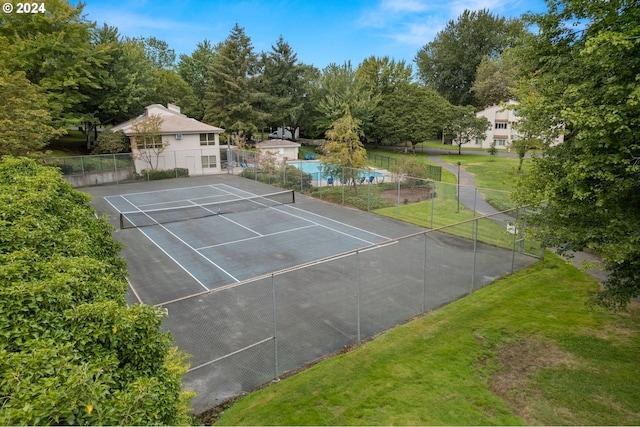 view of tennis court featuring a yard