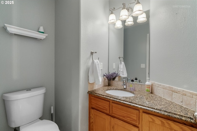 bathroom featuring toilet, an inviting chandelier, and vanity