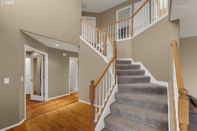 stairway with a towering ceiling and wood-type flooring