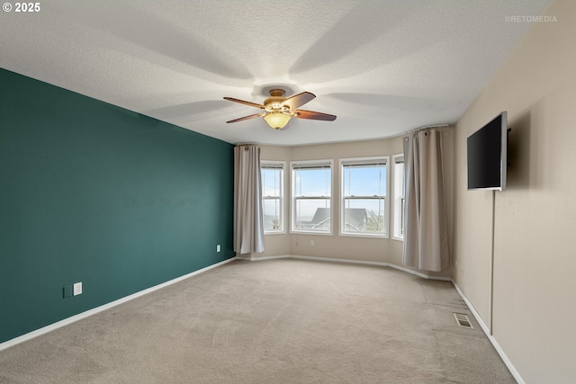 empty room featuring a textured ceiling, ceiling fan, and light colored carpet