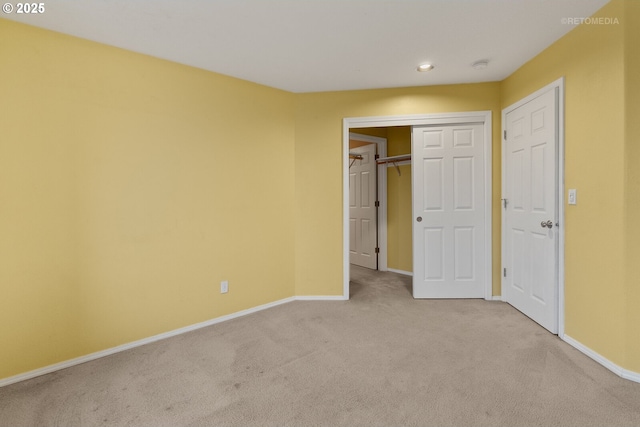 unfurnished bedroom with a closet and light colored carpet