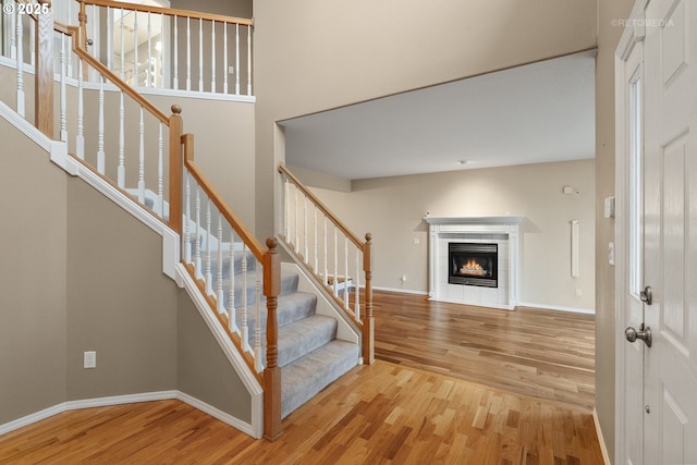 stairs featuring a tiled fireplace and hardwood / wood-style floors