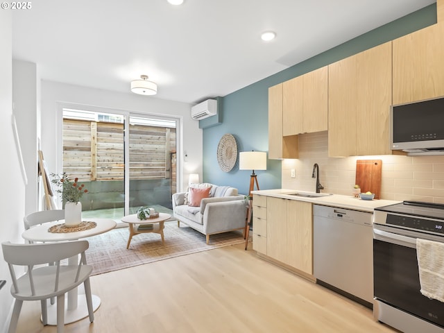 kitchen with a wall mounted air conditioner, stainless steel appliances, light hardwood / wood-style flooring, sink, and light brown cabinetry