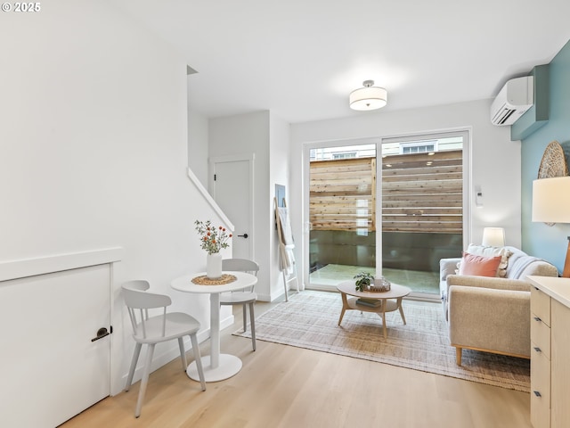 sitting room with a wall mounted air conditioner and light hardwood / wood-style flooring