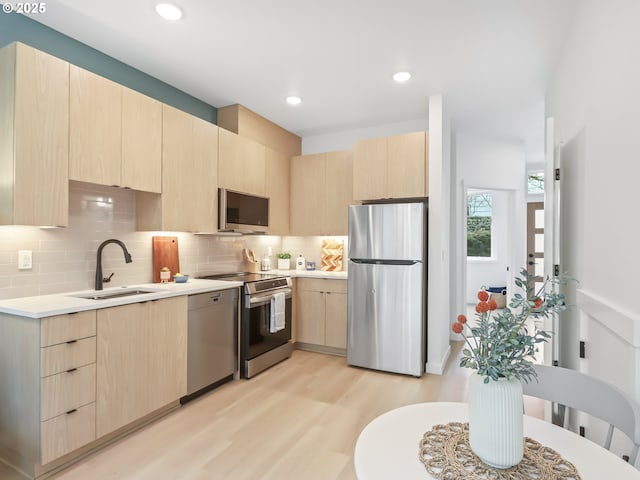 kitchen with light hardwood / wood-style flooring, sink, backsplash, appliances with stainless steel finishes, and light brown cabinets