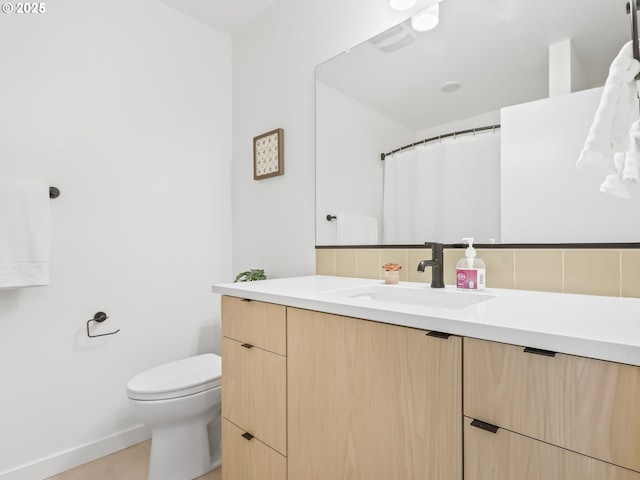 bathroom featuring vanity, toilet, and backsplash