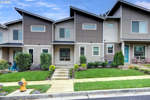 townhome / multi-family property featuring a front lawn and central AC