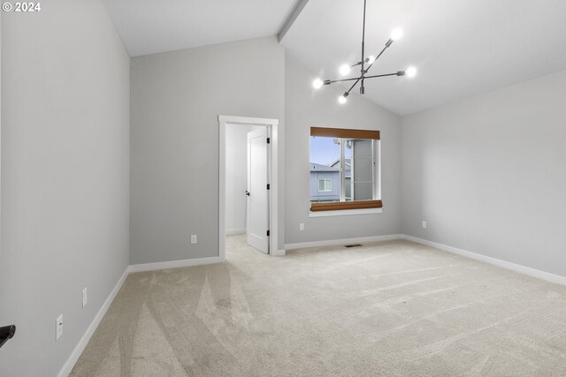 carpeted empty room with a chandelier and high vaulted ceiling