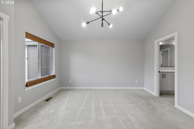 spare room featuring a chandelier, light carpet, and vaulted ceiling