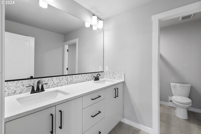 bathroom featuring vanity, tile patterned floors, a textured ceiling, and toilet