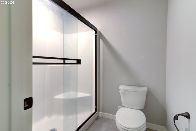 bathroom featuring toilet, walk in shower, and tile patterned floors