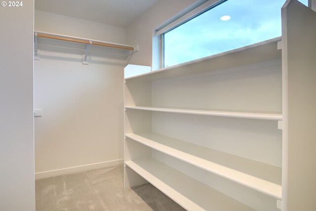 walk in closet featuring light colored carpet