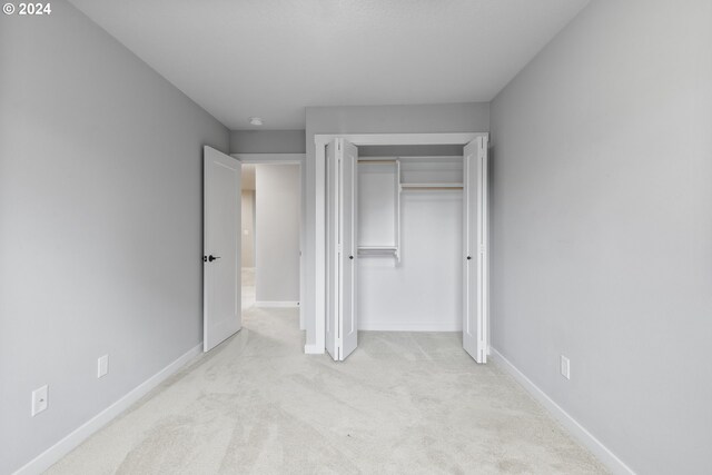 unfurnished bedroom featuring light carpet and a closet