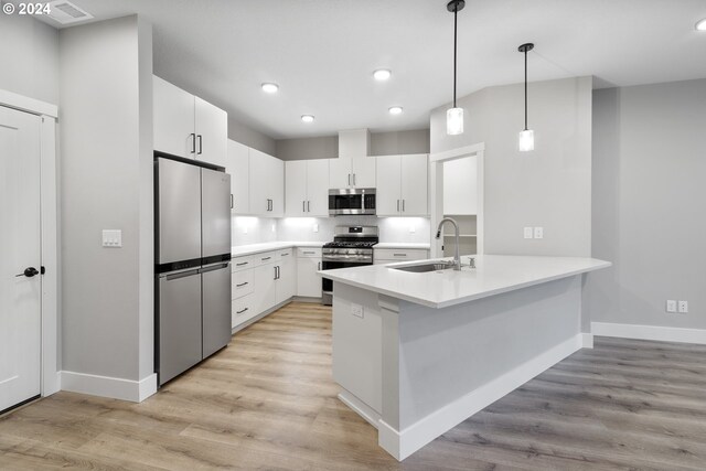 kitchen with light wood-type flooring, appliances with stainless steel finishes, hanging light fixtures, sink, and white cabinets