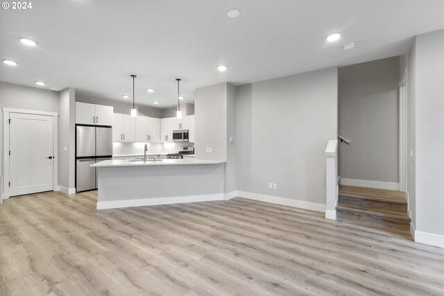 kitchen with white cabinetry, light wood-type flooring, stainless steel appliances, and decorative light fixtures