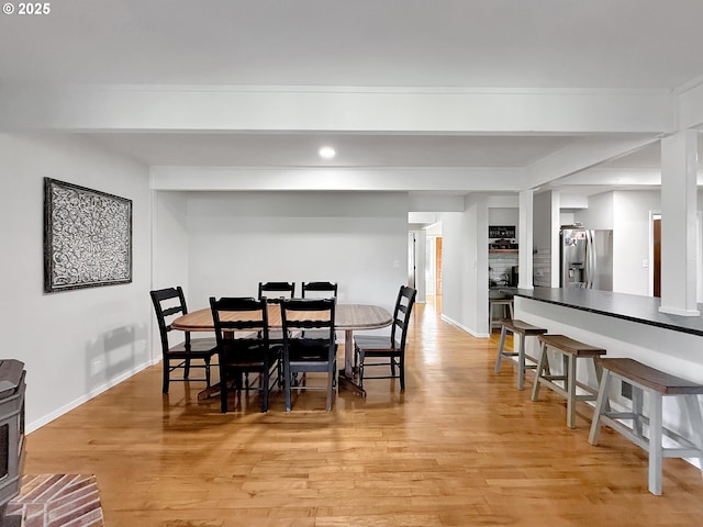 dining area featuring beam ceiling and light hardwood / wood-style flooring