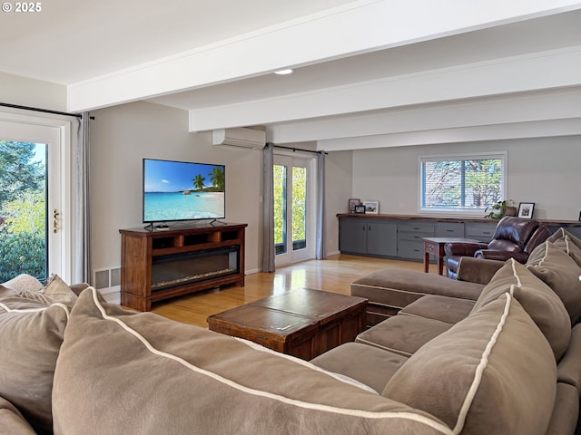 living room with light wood-type flooring, a wealth of natural light, beamed ceiling, and a wall unit AC