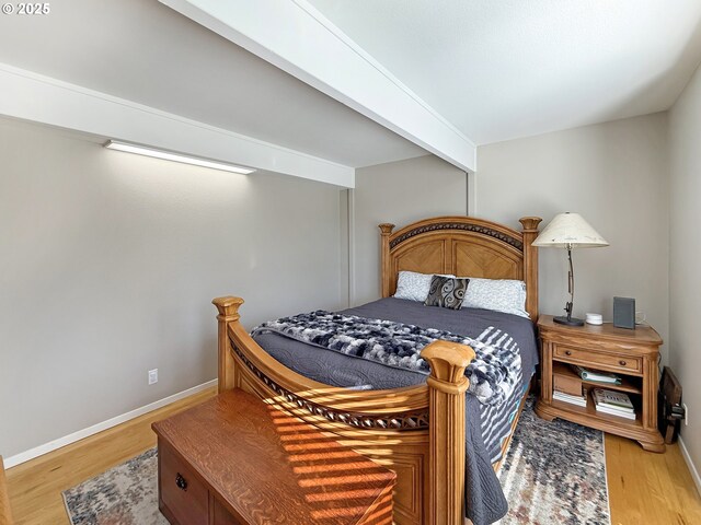 bedroom with hardwood / wood-style floors and beamed ceiling