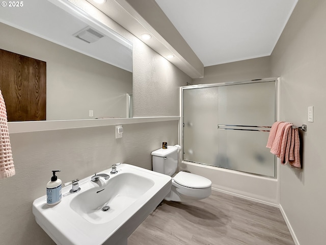 full bathroom with sink, bath / shower combo with glass door, toilet, and hardwood / wood-style floors