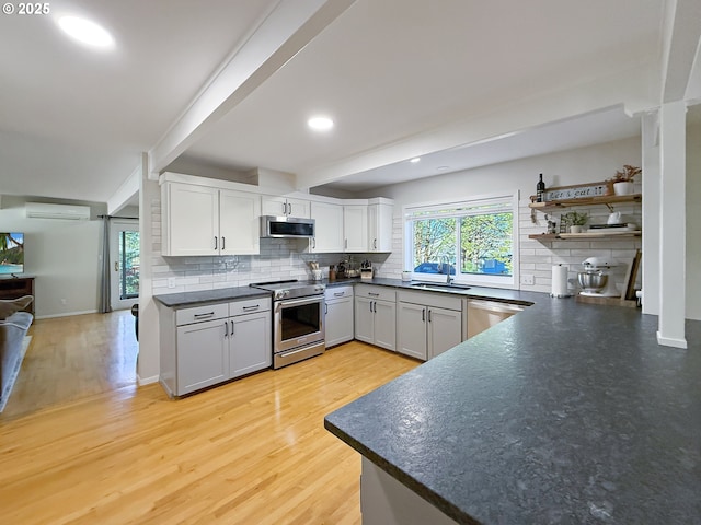 kitchen with white cabinetry, a wall unit AC, light hardwood / wood-style floors, tasteful backsplash, and appliances with stainless steel finishes