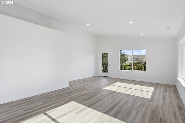 unfurnished room featuring lofted ceiling and light hardwood / wood-style flooring