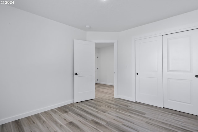 unfurnished bedroom with light wood-type flooring and a closet