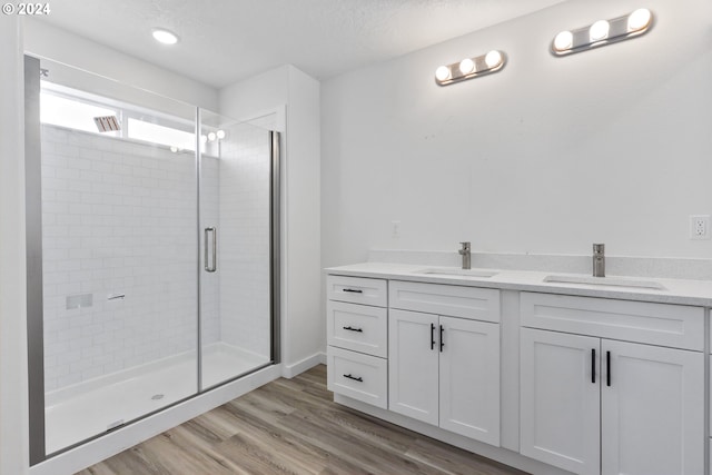 bathroom featuring a textured ceiling, a shower with door, vanity, and hardwood / wood-style flooring