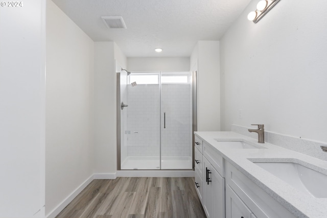 bathroom featuring walk in shower, wood-type flooring, a textured ceiling, and vanity