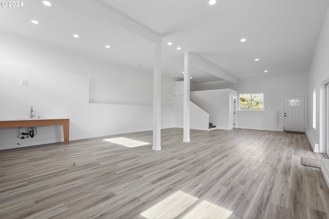 unfurnished living room with light hardwood / wood-style flooring and beam ceiling