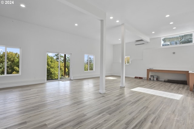 exercise room featuring a towering ceiling, light hardwood / wood-style flooring, and a wall mounted air conditioner