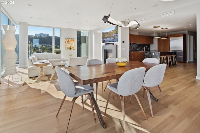 dining room featuring expansive windows, sink, and light hardwood / wood-style floors