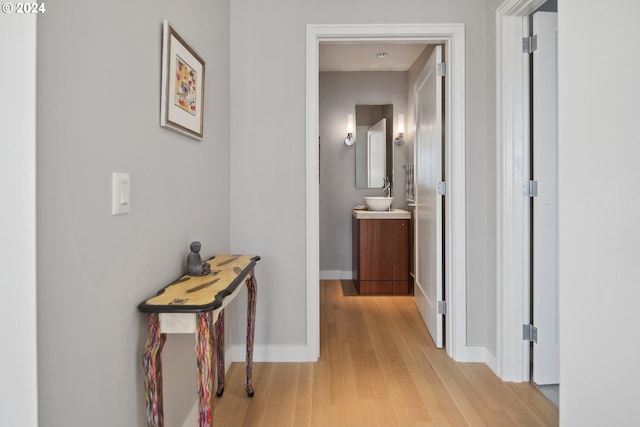 hall with light wood-type flooring and sink