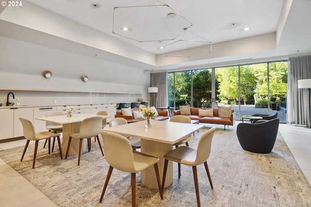 dining area featuring light tile patterned flooring, a tray ceiling, and sink