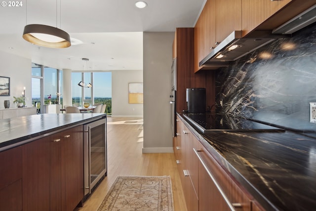 kitchen with light wood-type flooring, oven, black electric cooktop, decorative light fixtures, and wine cooler