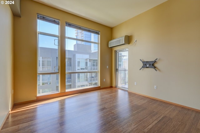 empty room featuring wood-type flooring and an AC wall unit