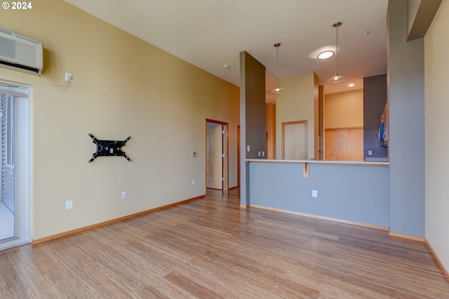 unfurnished living room with light wood-type flooring and a wall mounted AC