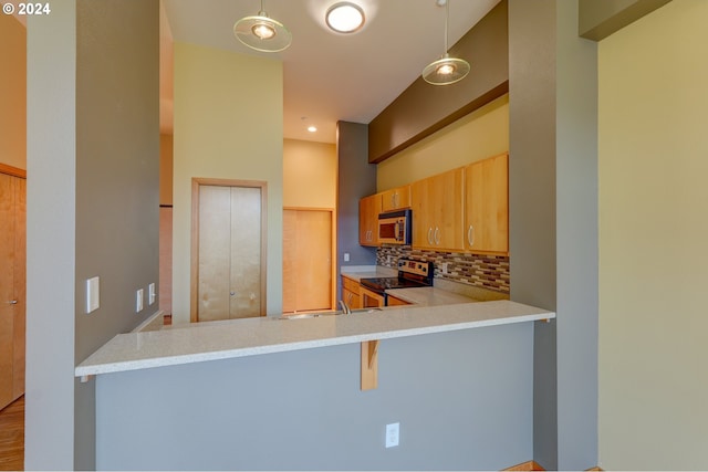 kitchen with tasteful backsplash, stainless steel electric range oven, a breakfast bar area, and hanging light fixtures