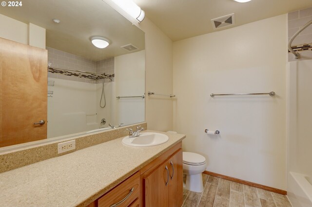 1125 NW 9th Ave Unit 524, Portland, OR 97209 - bathroom featuring shower / bathtub combination, vanity, toilet, baseboards, and wood finished floors