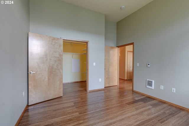 1125 NW 9th Ave Unit 524, Portland, OR 97209 - unfurnished bedroom featuring a high ceiling, wood finished floors, heating unit, and baseboards