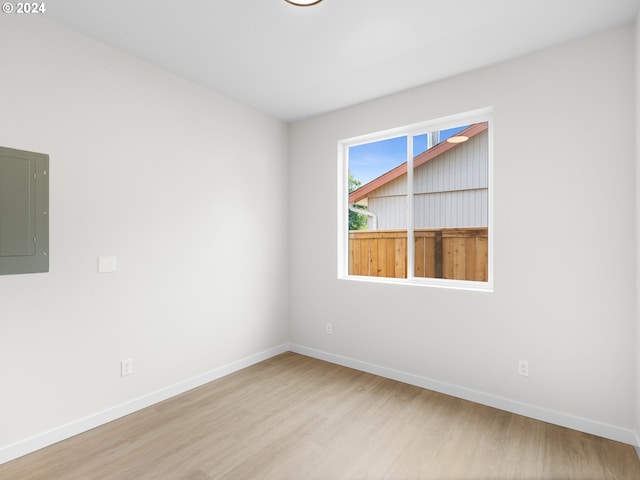 empty room with electric panel and light wood-type flooring