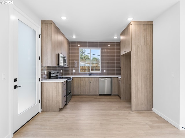 kitchen featuring backsplash, stainless steel appliances, sink, and light hardwood / wood-style flooring