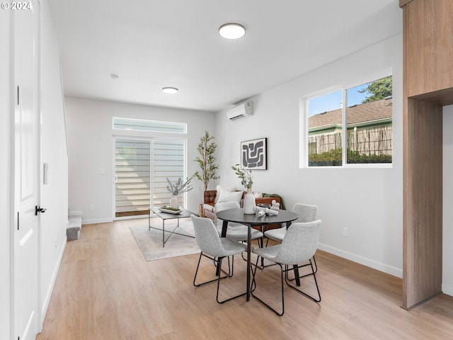 dining space featuring an AC wall unit and light wood-type flooring