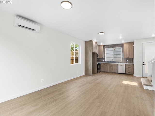 unfurnished living room with light hardwood / wood-style flooring, sink, and an AC wall unit