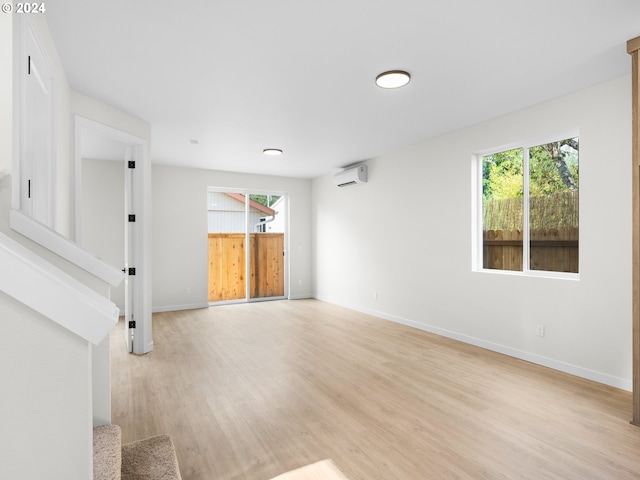 empty room with a wall unit AC and light hardwood / wood-style floors