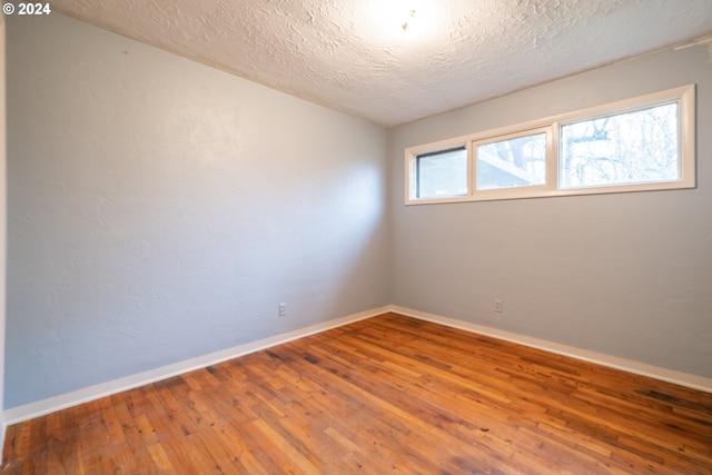 unfurnished room featuring wood-type flooring and a textured ceiling