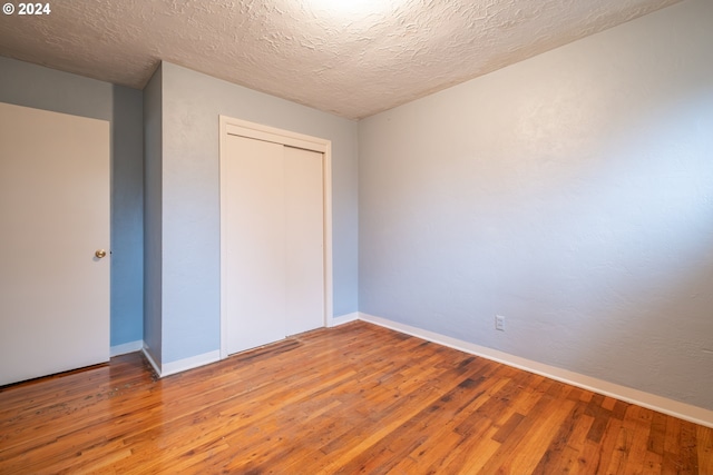 unfurnished bedroom featuring a closet, wood-type flooring, and a textured ceiling